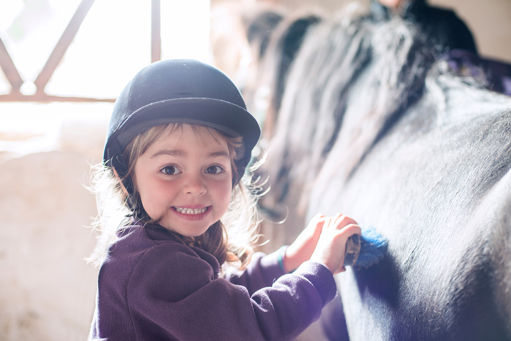 Little girl brushing her pony in the farm