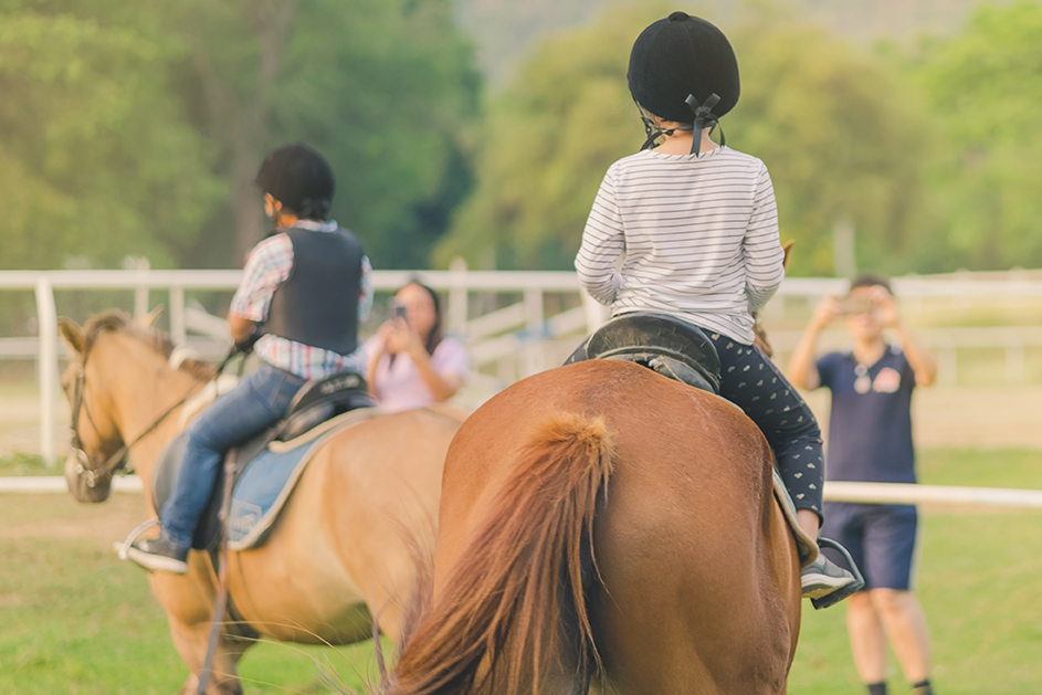 Kids learn to ride a horse near the river before sunset.