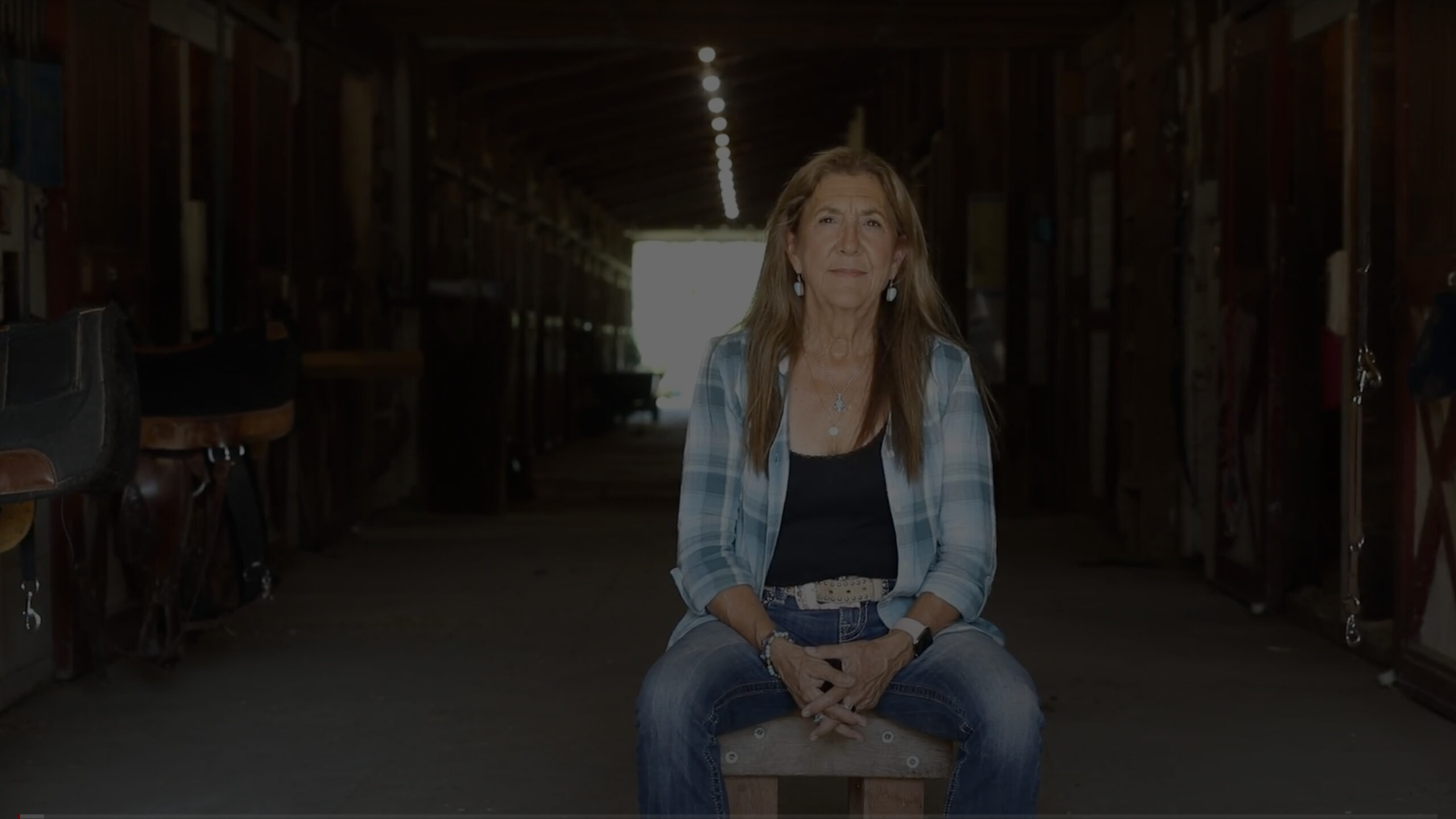 Owner Lynn sitting on stool in horse stables.